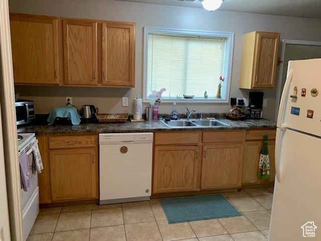 Kitchen with white appliances, sink, and light tile flooring