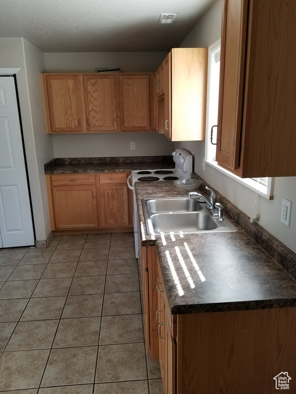 Kitchen featuring sink, electric range, and light tile floors