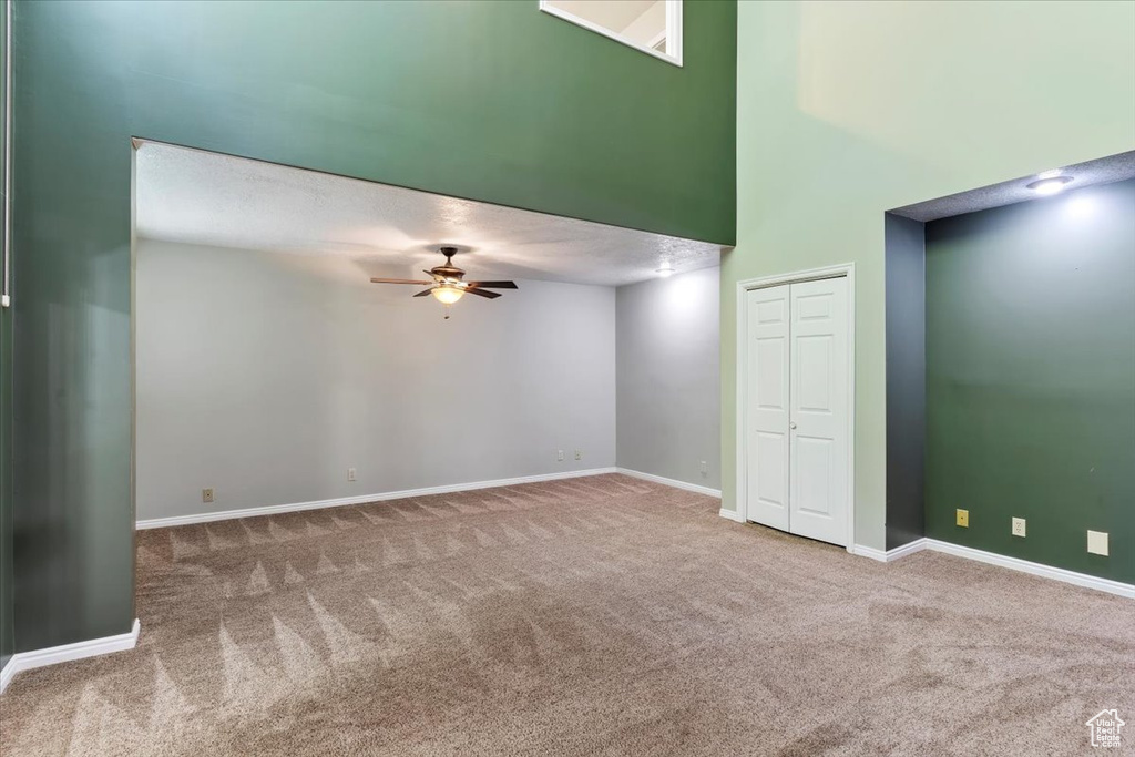 Carpeted empty room featuring high vaulted ceiling and ceiling fan