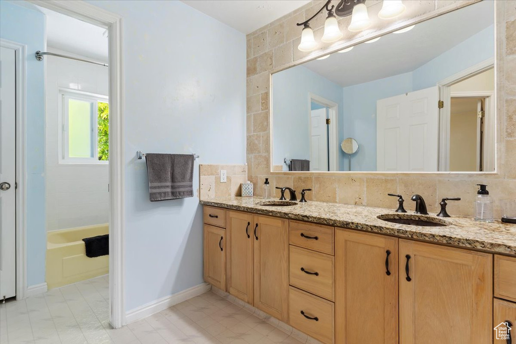 Bathroom featuring tile flooring, shower / washtub combination, double sink vanity, tile walls, and backsplash