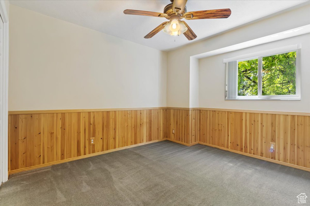 Unfurnished room with dark colored carpet and ceiling fan