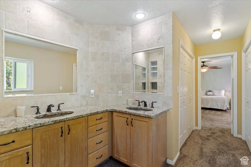 Bathroom with dual vanity, ceiling fan, tasteful backsplash, and tile walls