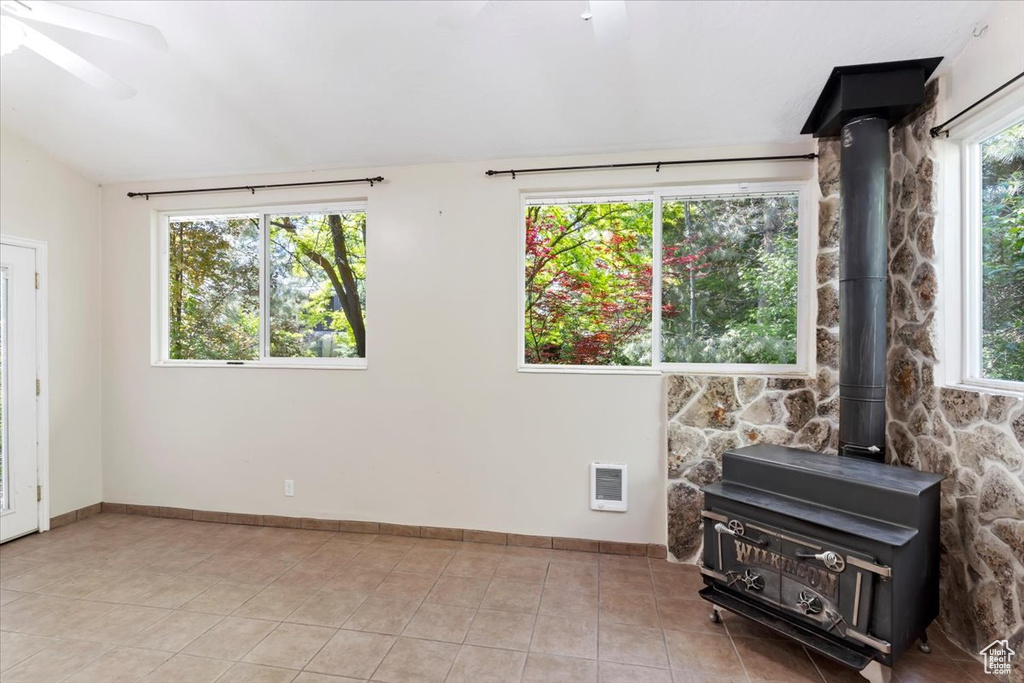 Spare room with a wealth of natural light, light tile flooring, and a wood stove