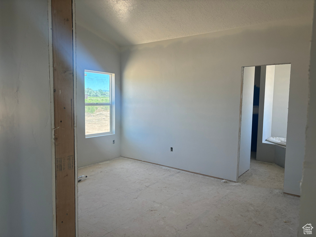 Unfurnished room with a textured ceiling and lofted ceiling