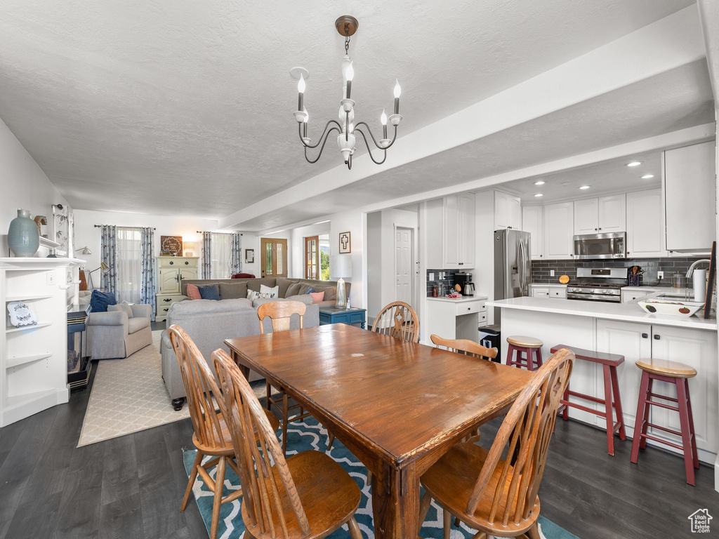 Dining space with dark hardwood / wood-style flooring, a textured ceiling, and a chandelier