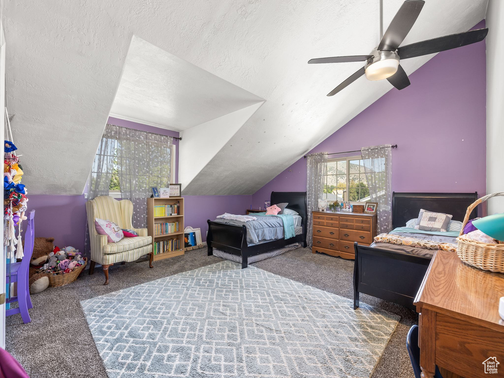 Bedroom featuring a textured ceiling, carpet flooring, ceiling fan, and vaulted ceiling