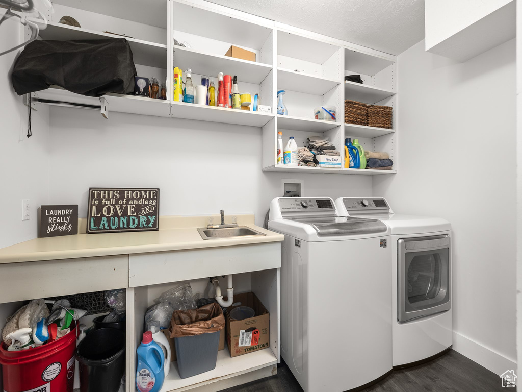 Laundry room featuring washer and clothes dryer, sink, and dark hardwood / wood-style floors