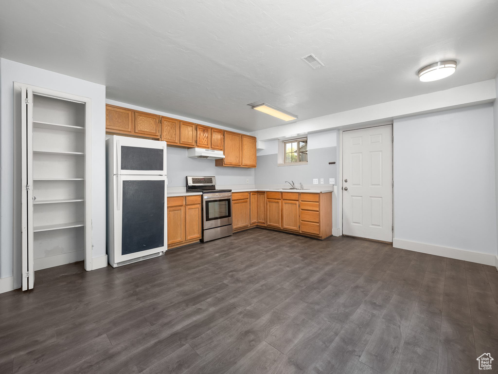 Kitchen with stainless steel electric range, sink, white fridge, and dark wood-type flooring