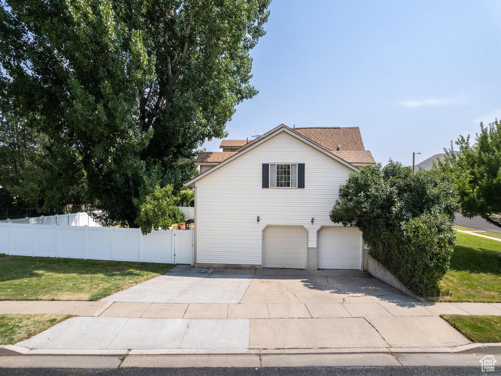 View of side of home with a garage and a lawn