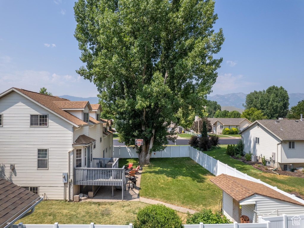 Exterior space featuring a patio area, a lawn, and a deck with mountain view