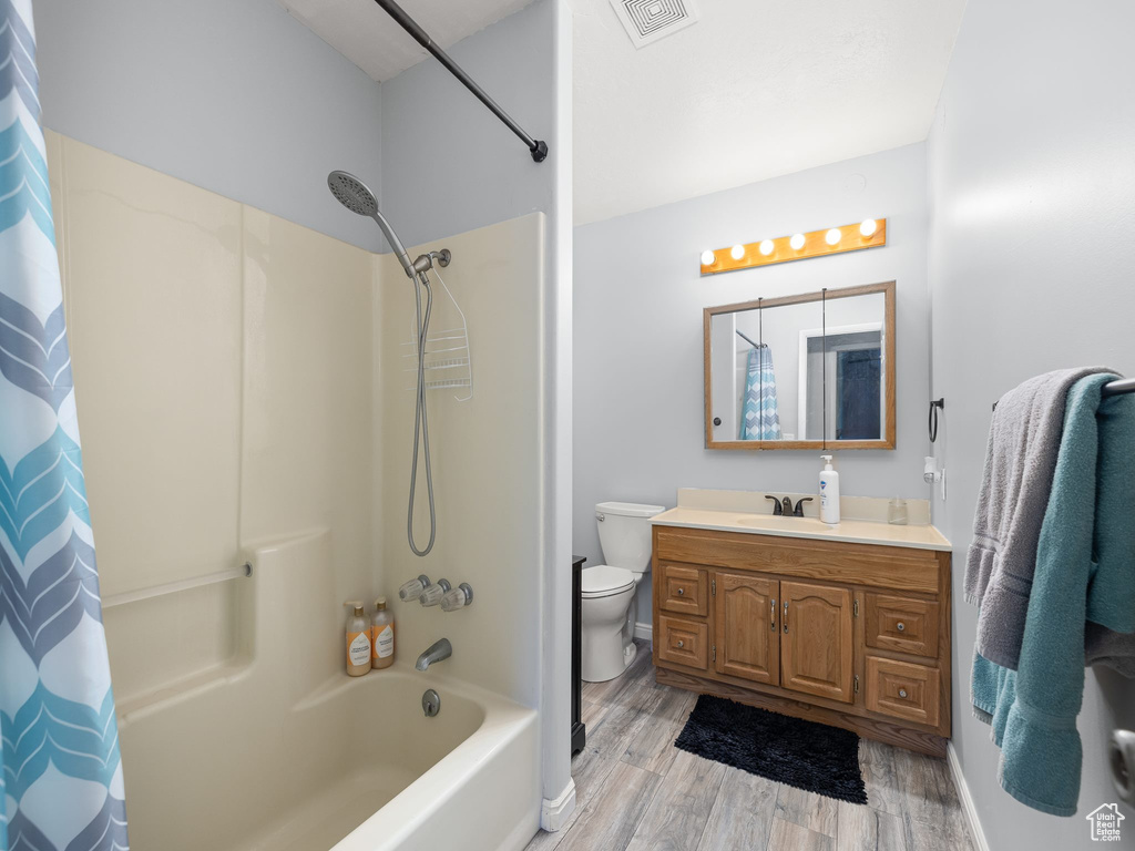 Full bathroom with shower / bath combination with curtain, wood-type flooring, toilet, and large vanity