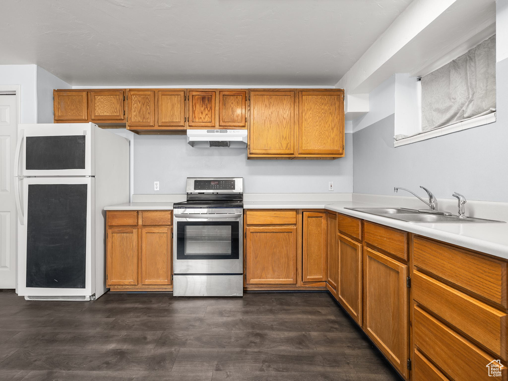 Kitchen with dark hardwood / wood-style floors, stainless steel range with electric cooktop, white fridge, and sink