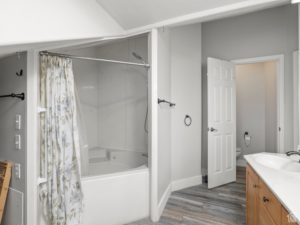 Full bathroom featuring shower / bath combination with curtain, hardwood / wood-style floors, toilet, and vanity