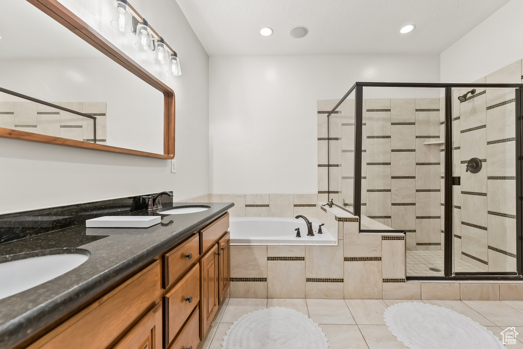 Bathroom featuring tile flooring, independent shower and bath, and double sink vanity