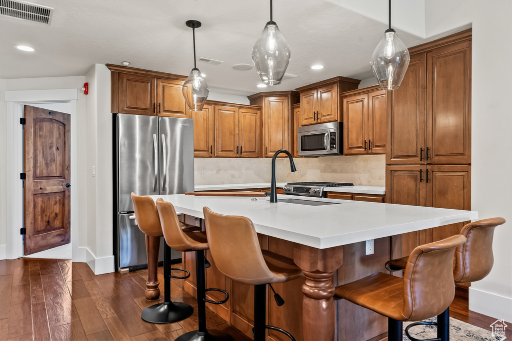 Kitchen with decorative light fixtures, dark hardwood / wood-style flooring, tasteful backsplash, and stainless steel appliances