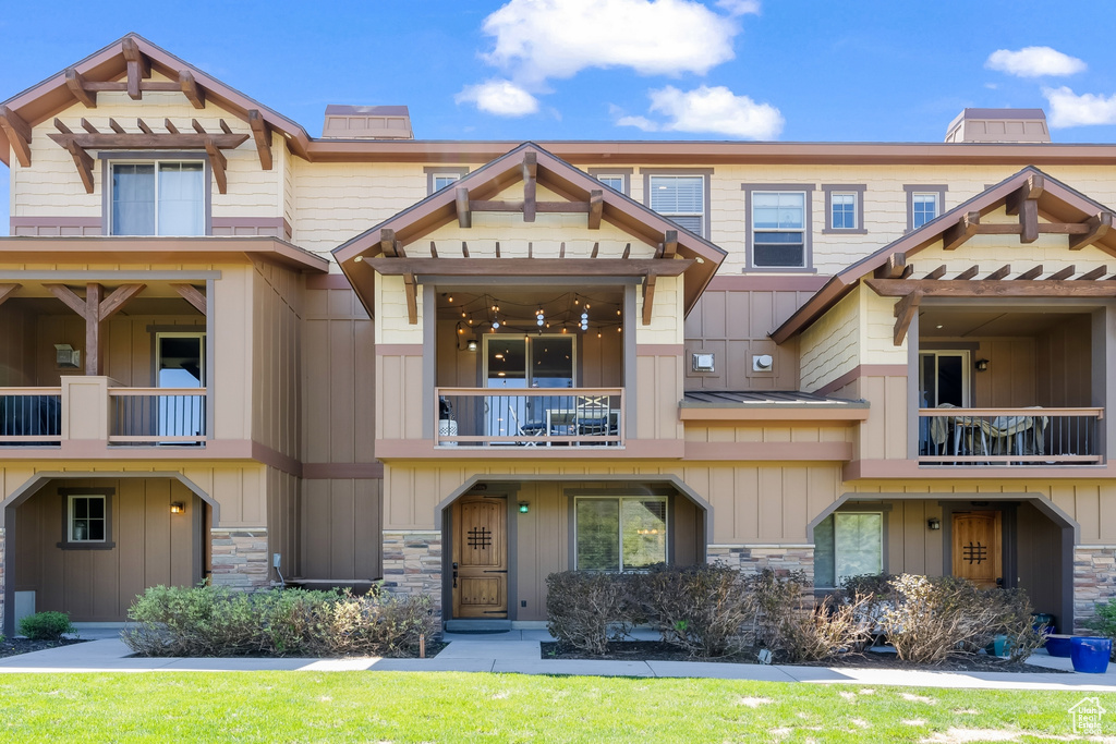 View of front of home with a front yard and a balcony