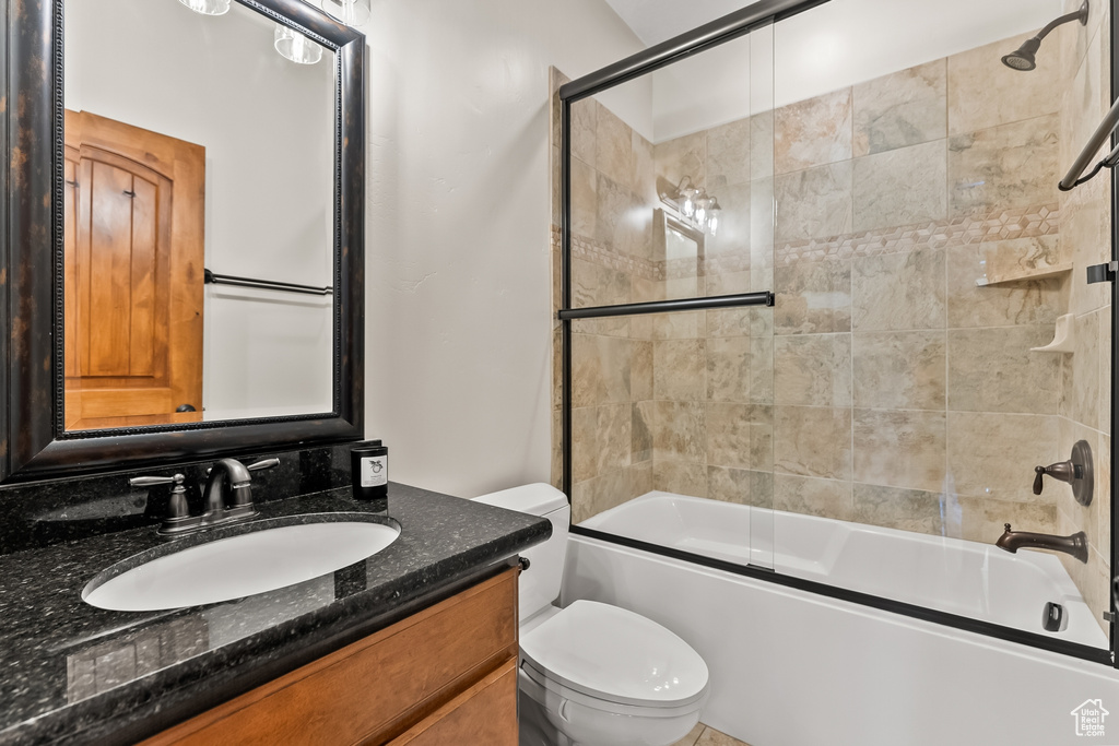 Full bathroom featuring shower / bath combination with glass door, toilet, and vanity