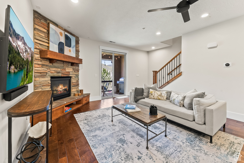 Living room featuring a stone fireplace, ceiling fan, and hardwood / wood-style floors