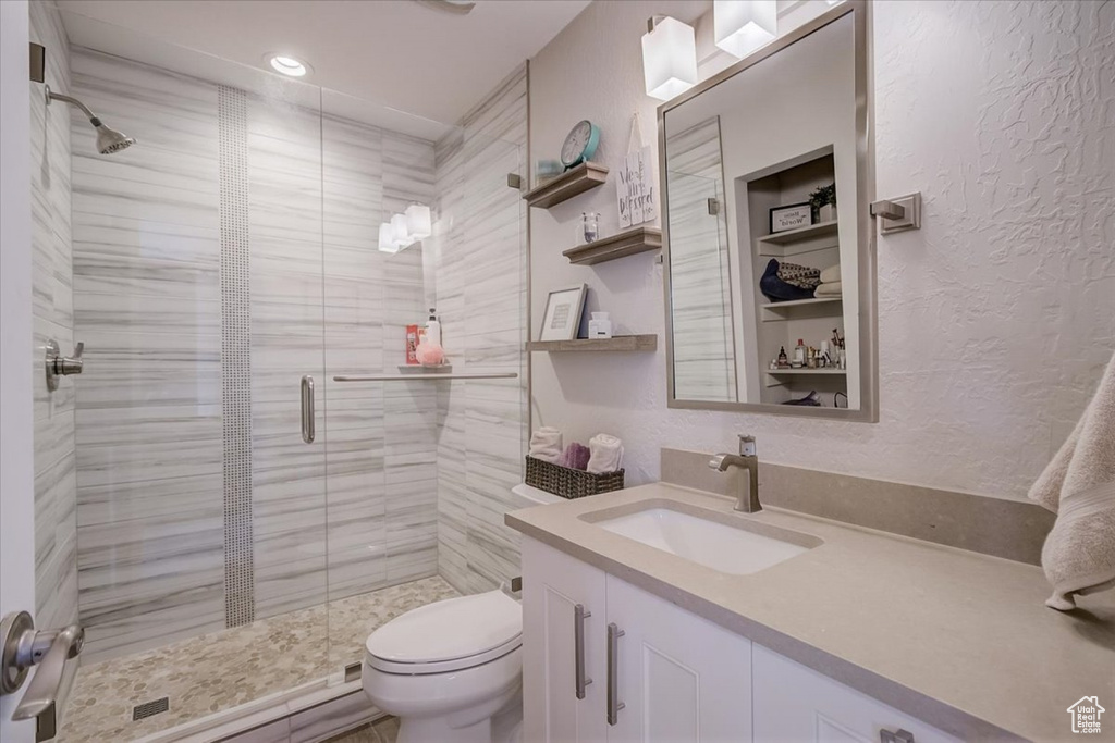 Bathroom featuring an enclosed shower, vanity, and toilet