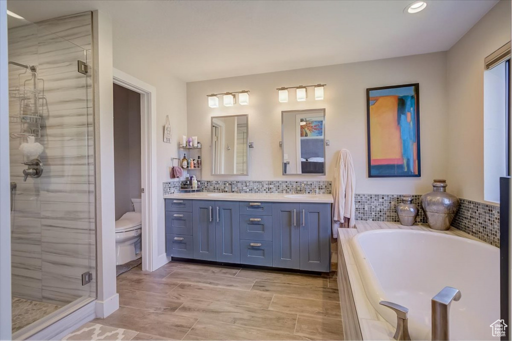 Full bathroom with double vanity, tasteful backsplash, separate shower and tub, and toilet