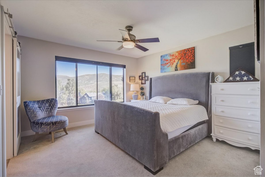 Bedroom with light colored carpet, a mountain view, and ceiling fan