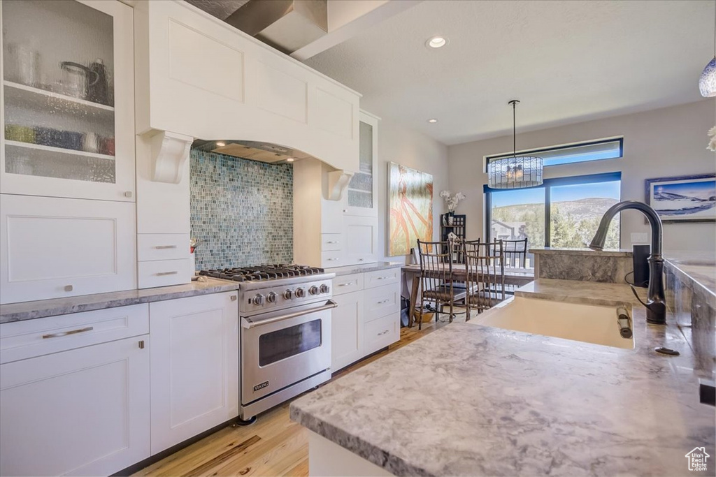 Kitchen with gas stove, an inviting chandelier, white cabinets, and backsplash