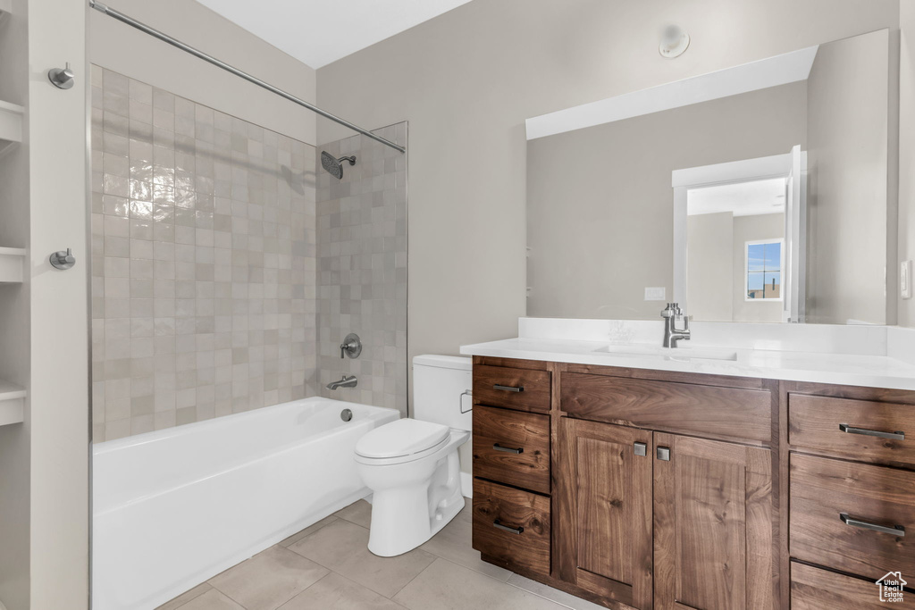 Full bathroom featuring tile flooring, toilet, vanity, and tiled shower / bath