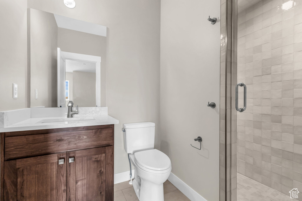 Bathroom featuring tile floors, walk in shower, toilet, and vanity with extensive cabinet space