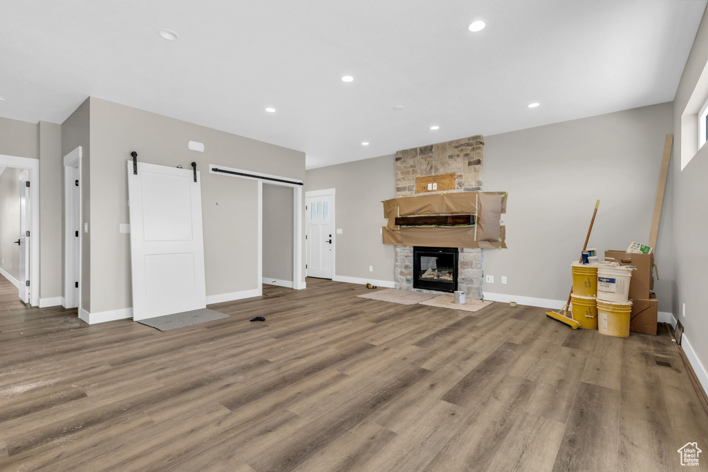 Living room featuring a barn door, hardwood / wood-style flooring, and a stone fireplace