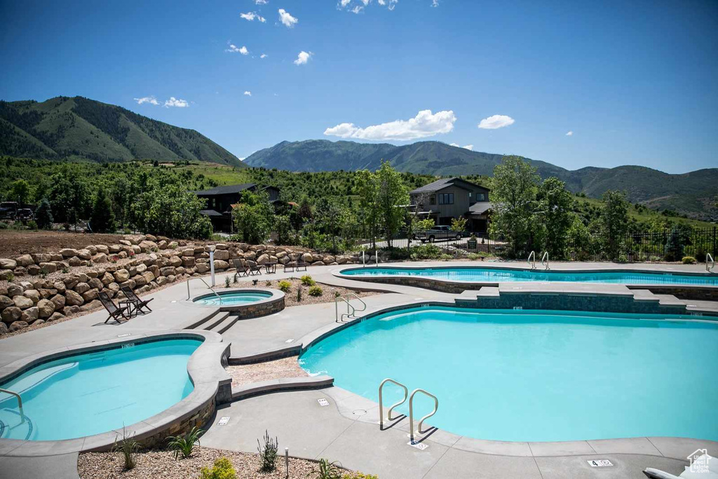 View of swimming pool with a mountain view and a hot tub