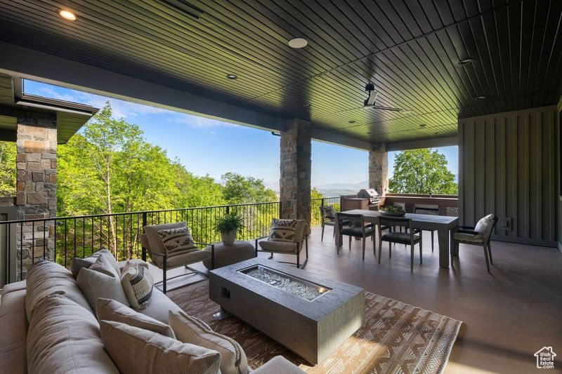 View of patio with an outdoor living space with a fire pit and a balcony