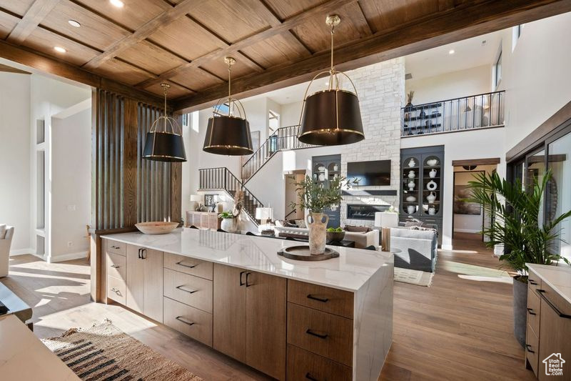 Kitchen featuring beam ceiling, a fireplace, pendant lighting, wood ceiling, and wood-type flooring