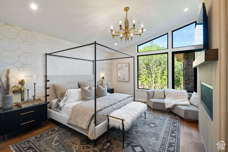 Bedroom featuring dark hardwood / wood-style floors, high vaulted ceiling, and a chandelier