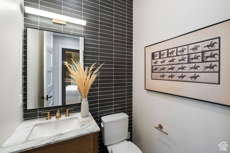 Bathroom with tile walls, tasteful backsplash, toilet, and vanity