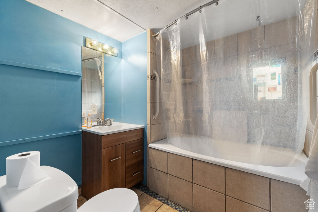 Full bathroom featuring tile floors, shower / bath combination with curtain, toilet, and vanity with extensive cabinet space