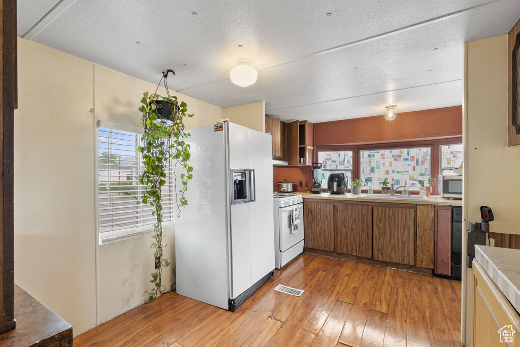 Kitchen featuring sink, white appliances, and light wood-type flooring
