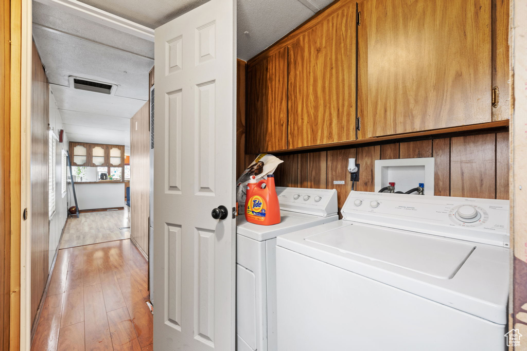 Laundry room featuring hookup for a washing machine, washing machine and clothes dryer, light wood-type flooring, and cabinets