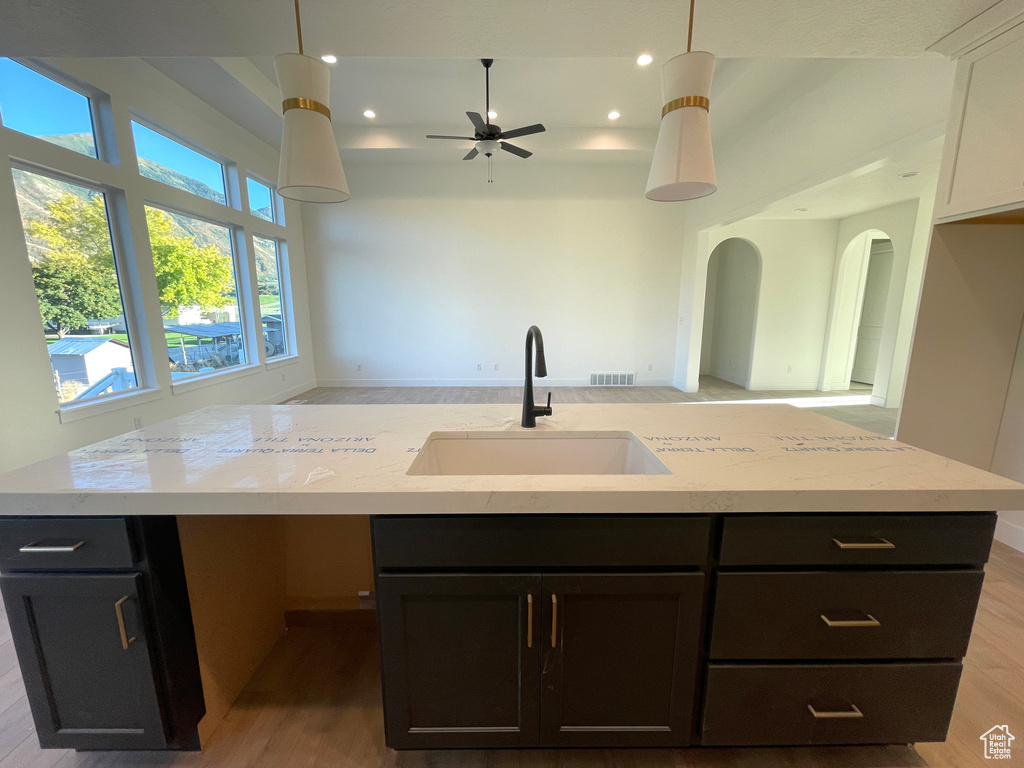 Kitchen with a kitchen island with sink, ceiling fan, pendant lighting, and hardwood / wood-style flooring