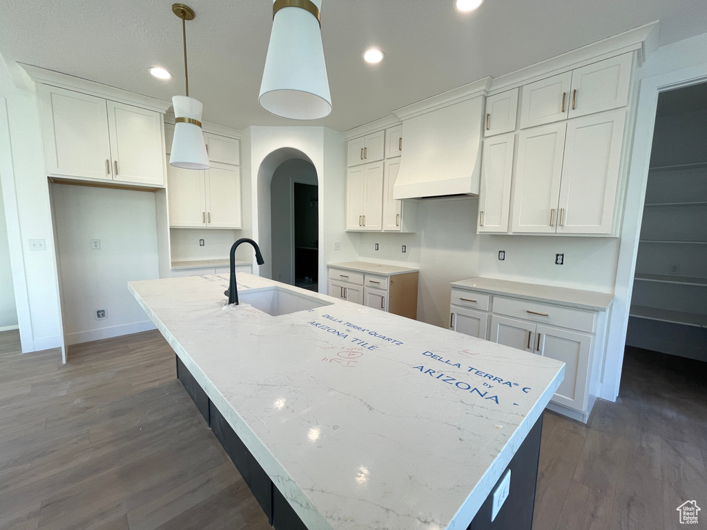 Kitchen featuring a center island with sink and white cabinetry