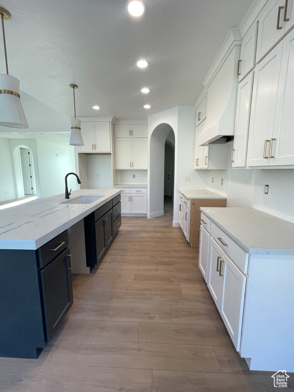 Kitchen featuring a large island, hanging light fixtures, sink, and white cabinetry