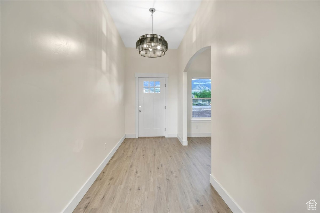 Doorway to outside with light hardwood / wood-style floors and an inviting chandelier