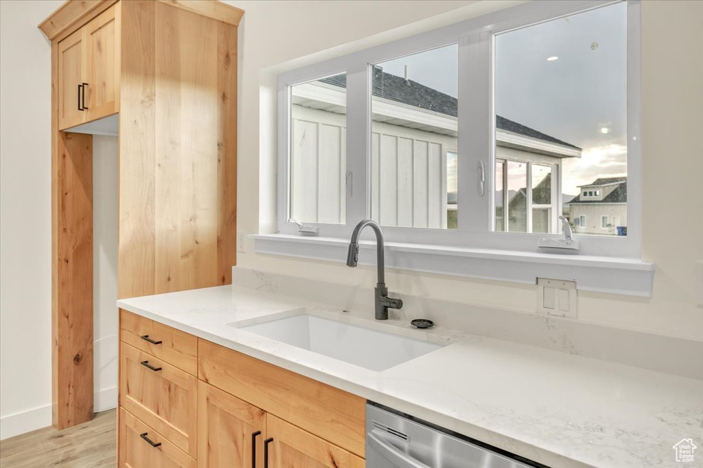 Kitchen with light stone countertops, sink, light wood-type flooring, and light brown cabinetry