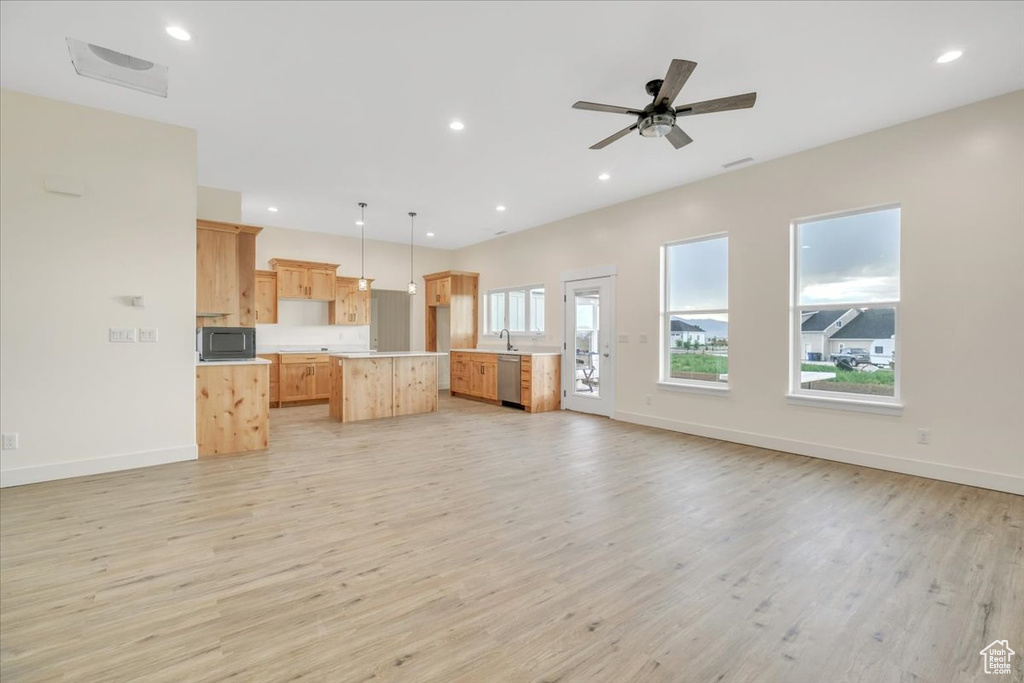 Unfurnished living room featuring ceiling fan, sink, and light hardwood / wood-style flooring