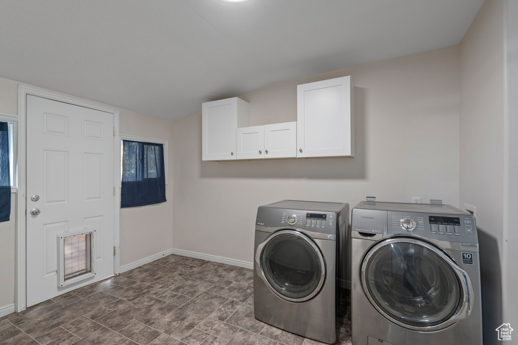 Laundry area featuring tile flooring, cabinets, and washer and dryer