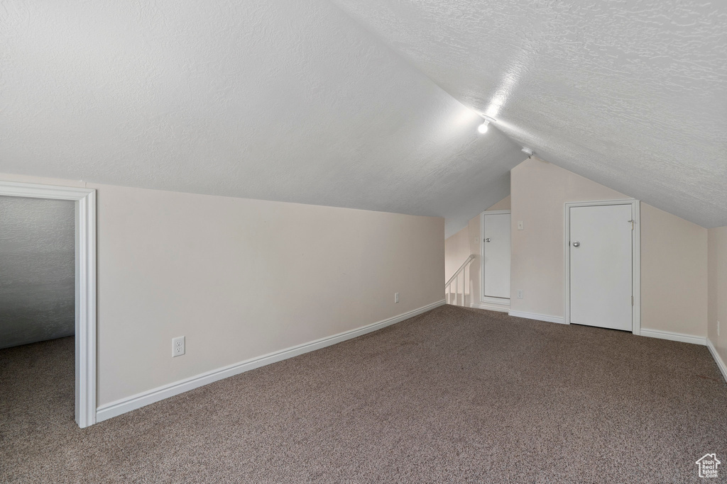 Bonus room featuring a textured ceiling, vaulted ceiling, and carpet