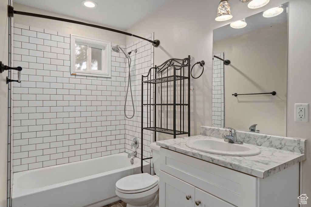 Full bathroom featuring vanity with extensive cabinet space, toilet, and tiled shower / bath combo