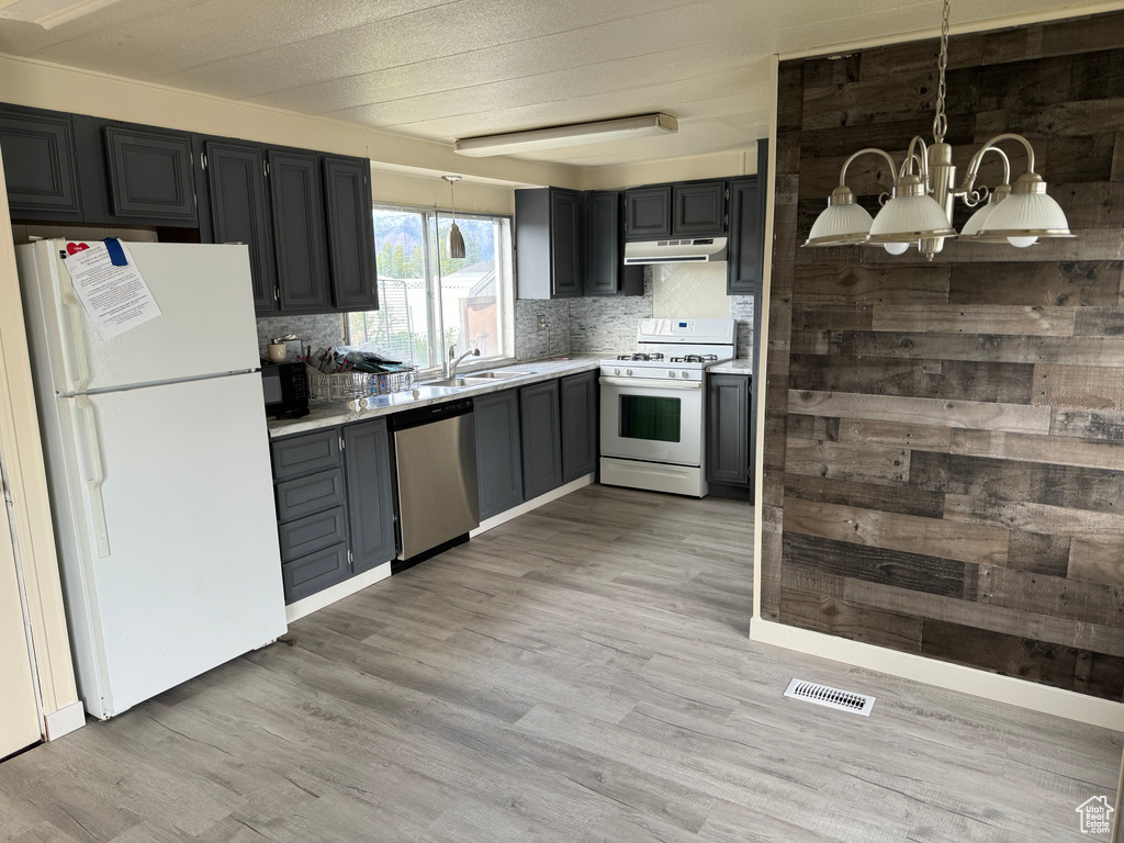 Kitchen featuring light hardwood / wood-style flooring, white appliances, an inviting chandelier, and backsplash