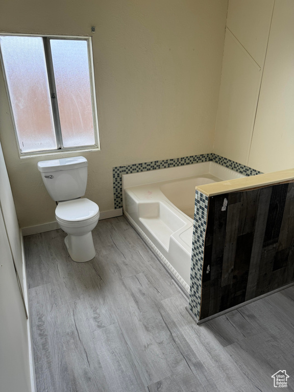 Bathroom with a bathtub, toilet, and wood-type flooring