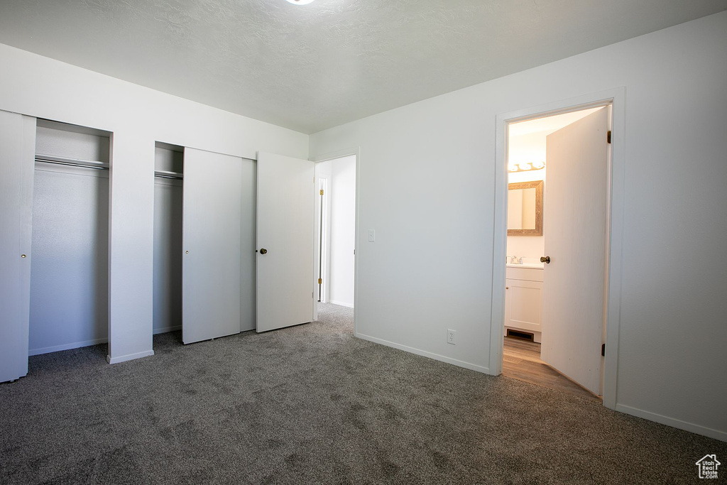 Unfurnished bedroom featuring multiple closets, hardwood / wood-style flooring, and connected bathroom