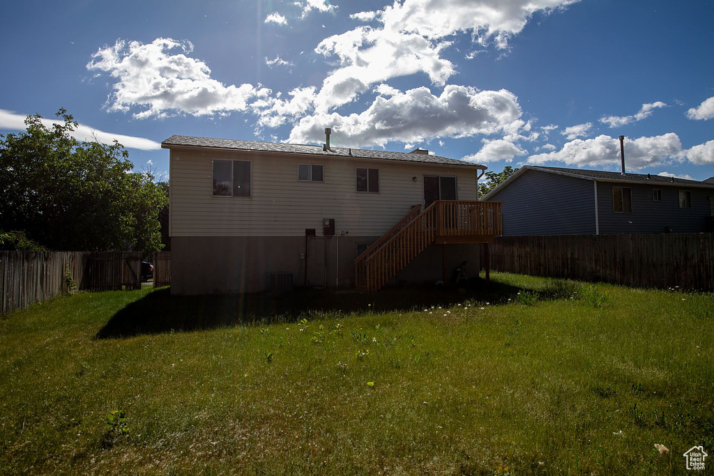 Back of house with a deck and a yard